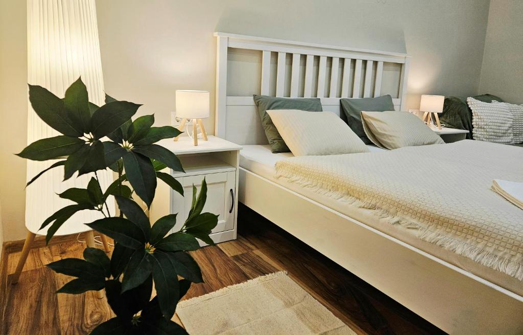 久洛Lilien Deluxe的一间卧室,配有床和花瓶中的植物