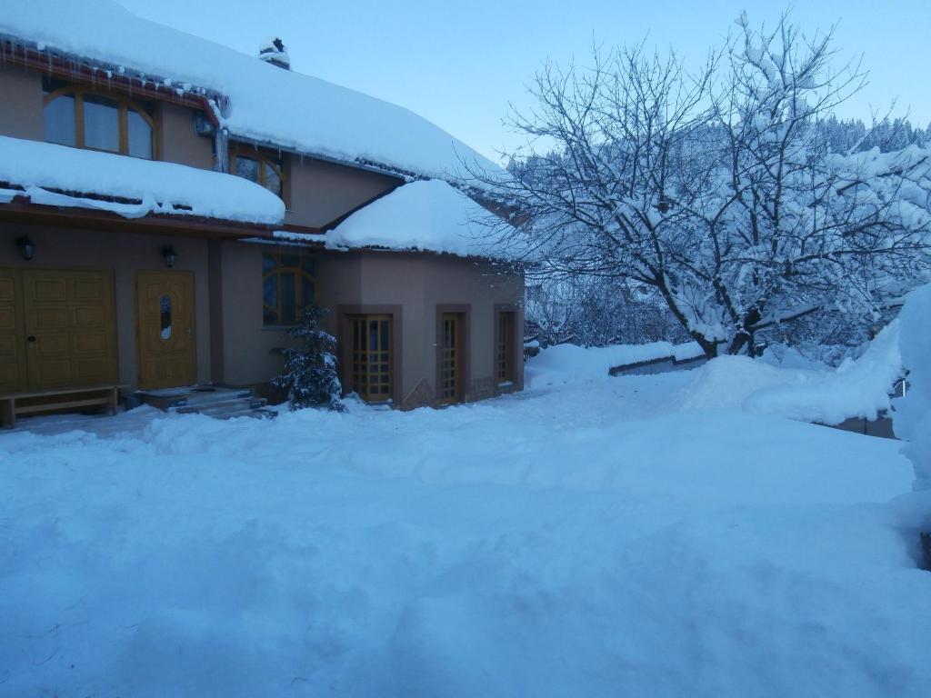 a house with snow on the front of it at Karpatskiy Domik Izki in Izki