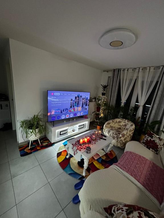 Una sala de estar con un televisor y una mesa. en Apparemment 3 pièce Strasbourg Ilkirch graffenstaden, en Illkirch-Graffenstaden