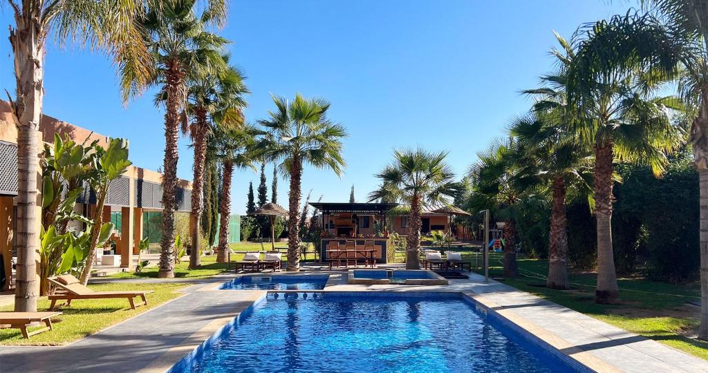 una piscina con palmeras frente a una casa en Maison d'Hotes Oasis Marrakech Route dOuarzazate, en Oulad Akkou