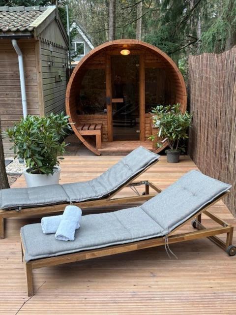 two lounge chairs on a deck with a gazebo at Forest house with sauna in Norg