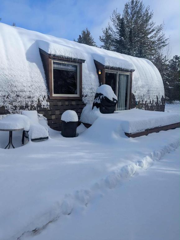 a snow covered house with a yard covered in snow at POD'Stress Nature et Tranquilité in Saint-Alexis-des-Monts
