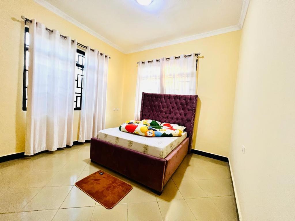 een slaapkamer met een bed en een raam met gordijnen bij CnRAirBnB in Iringa