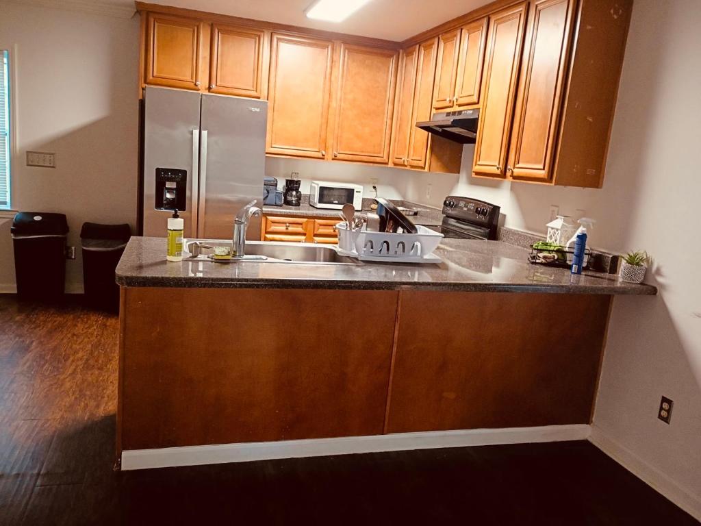 a kitchen with wooden cabinets and a stainless steel refrigerator at Fletcher Street Hideaway Room 8 with Cozy Vibes in Atlanta