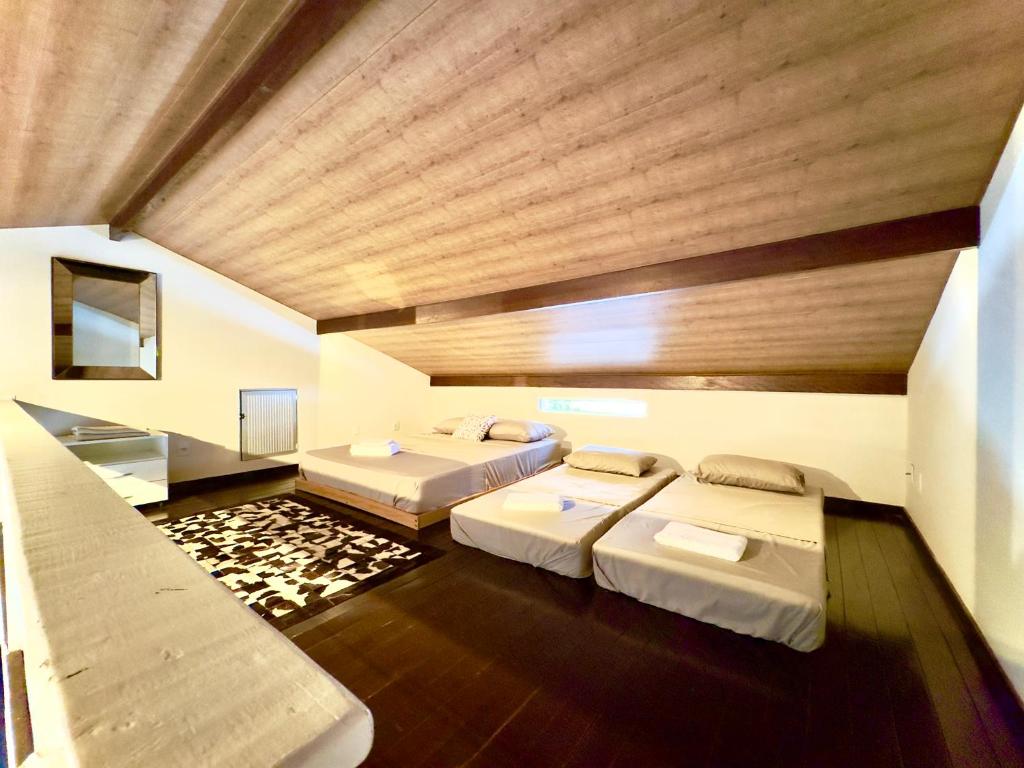 two beds in a large room with wooden ceilings at Casa Completa com Piscina Churrasqueira Wi-Fi a 300m da Praia Acomoda 10 Pessoas, 3 Quartos com Ar-Condicionado in Penha