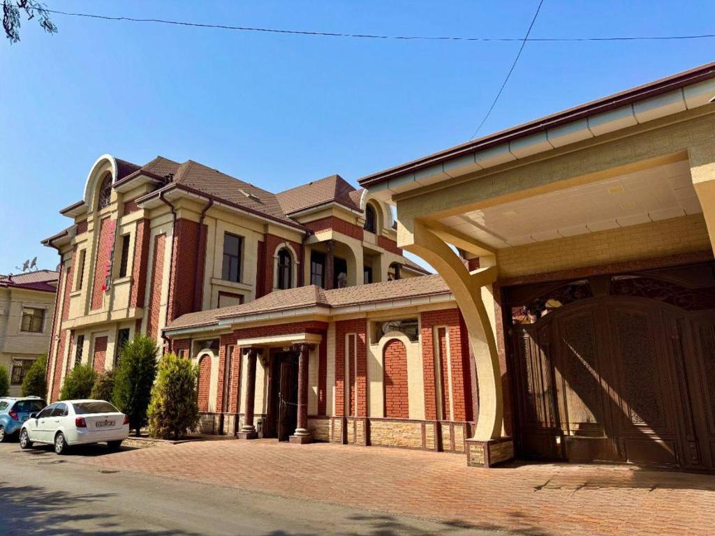 a large brick building with a car parked in front of it at Cosmos Hotel in Yakkasaray