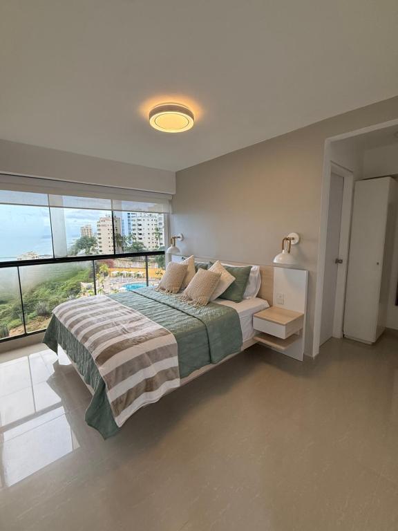 um quarto com uma cama e uma janela grande em Oceanfront Playa Grande 10 min Airport Aeropuerto em Maiquetía