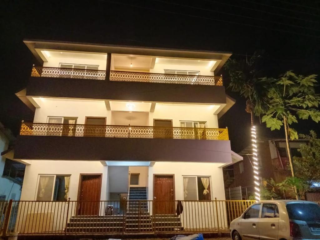 a white building with a balcony and a car parked in front at Hare Krishna Beach Resort in Srīvardhan