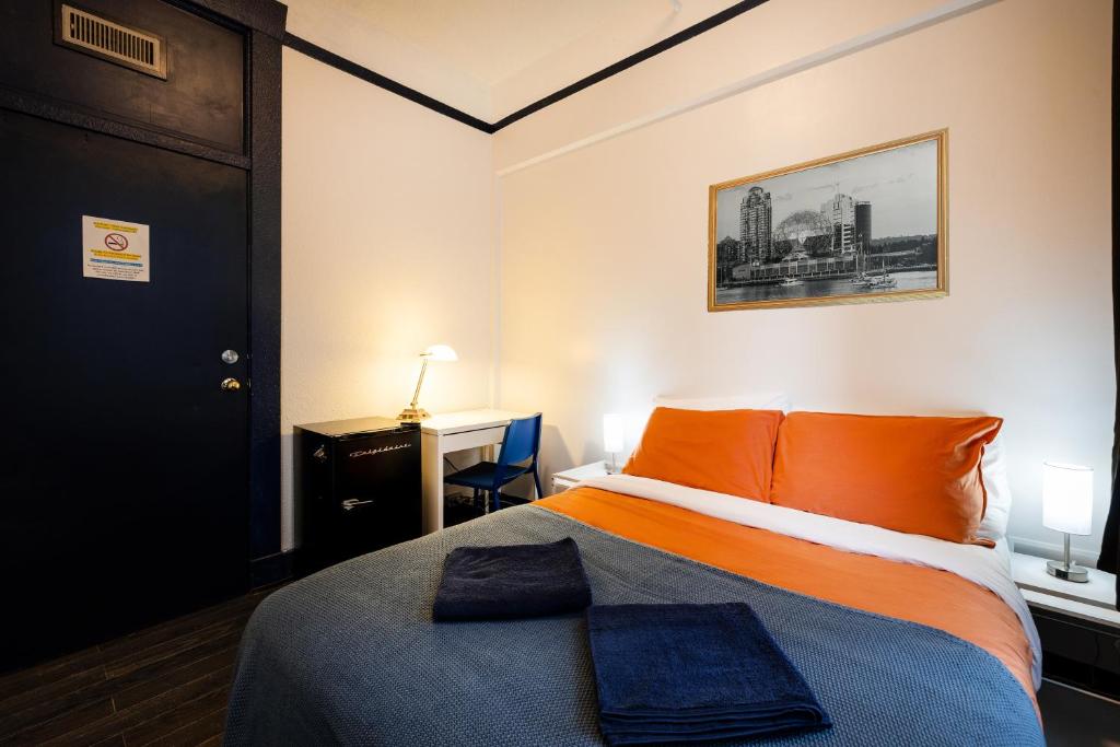 a bedroom with a bed with orange pillows on it at The Guesthouse Vancouver Downtown in Vancouver