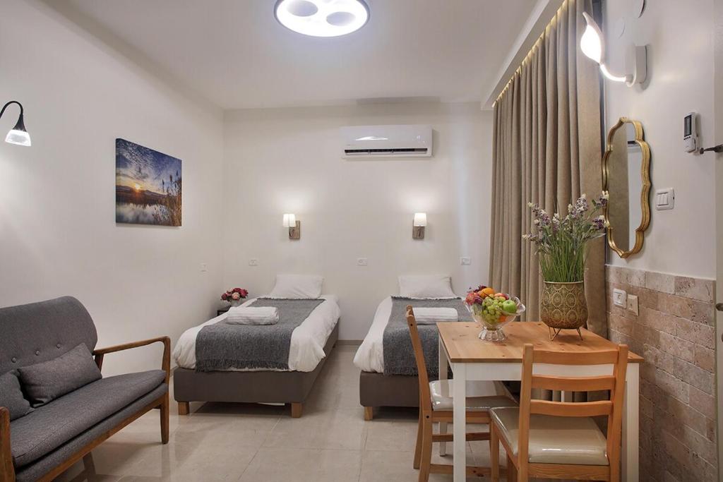 a room with two beds and a table and a couch at Melony Tsfat in Safed