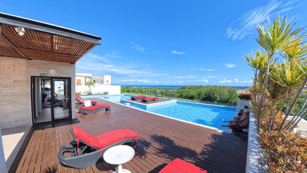 a deck with red chairs and a swimming pool at Grand Fifty Suites in Playa del Carmen