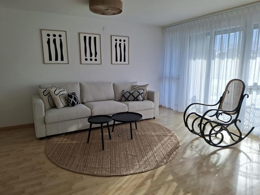 een woonkamer met een bank, een tafel en stoelen bij Summit View Apartment in Spiez