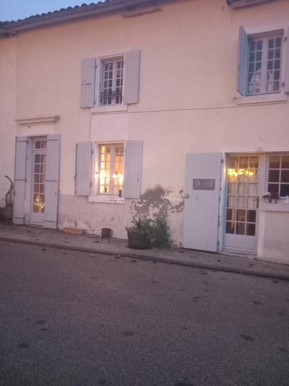 a white house with lights in the windows at La maison aux livres in Rioux-Martin