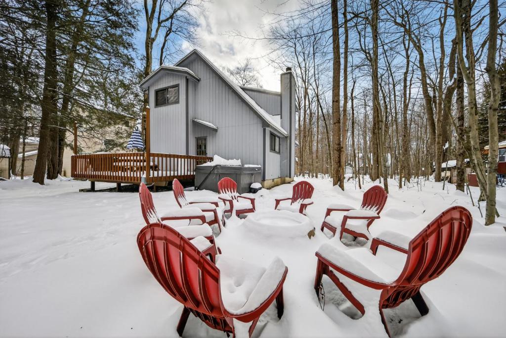 a table and chairs covered in snow in front of a house at Private Pocono Retreat with Hot Tub and Fire Pit in Thornhurst