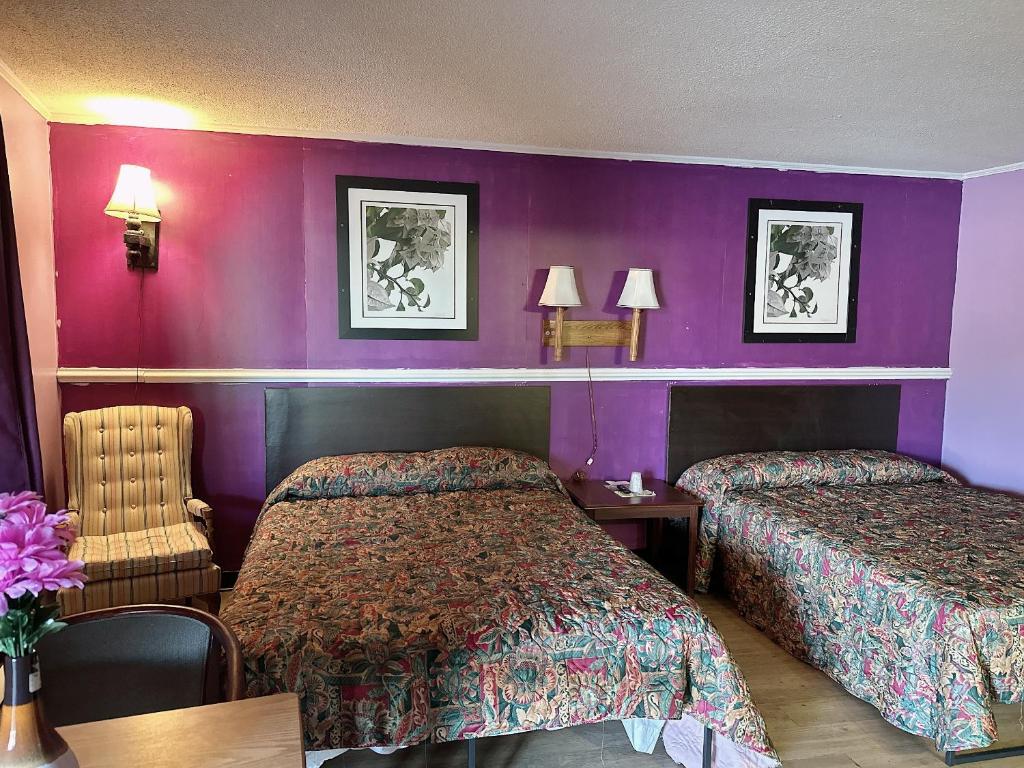 una camera d'albergo con due letti e pareti viola di Riverside inn motel a Plymouth
