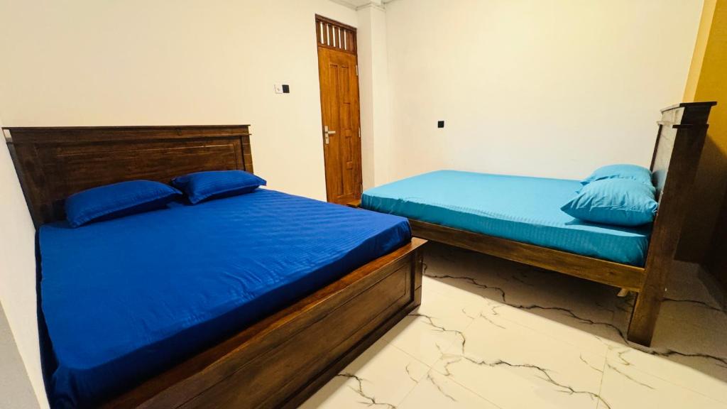een slaapkamer met twee bedden met blauwe kussens erop bij Madinah Comfort Inn in Colombo