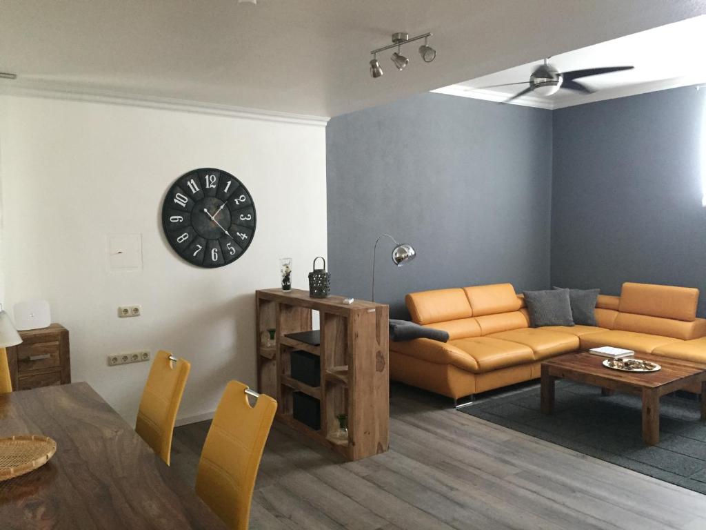 a living room with a couch and a clock on the wall at Ferienwohnung Würzburg Sanderau in Würzburg