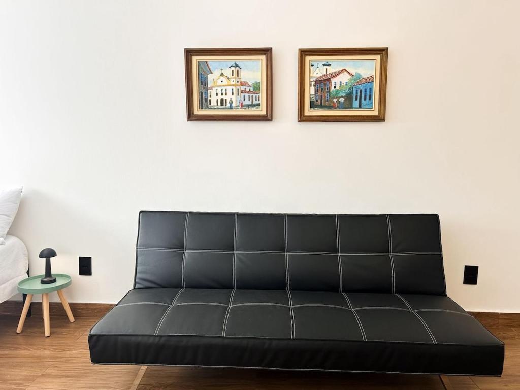 AP Smart City Life Flat في كامبيناس: أريكة سوداء في غرفة معيشة مع صورتين على الحائط