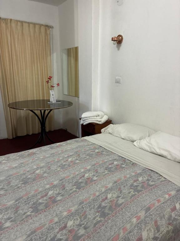 a hotel room with a bed and a table at Hotel Los Proceres in La Aurora