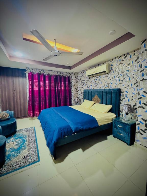 The Diplomat Suites Bahria Town في روالبندي: غرفة نوم بسرير ازرق وستائر حمراء