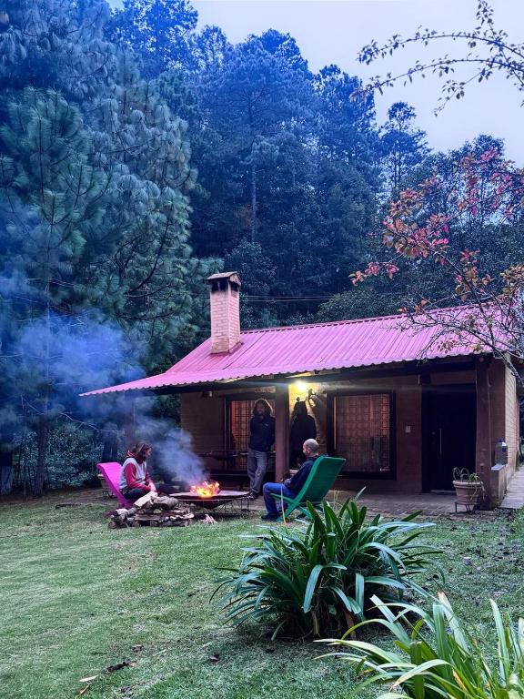 a group of people sitting around a fire in front of a house at cabaña de adobe las moras in San Mateo Río Hondo