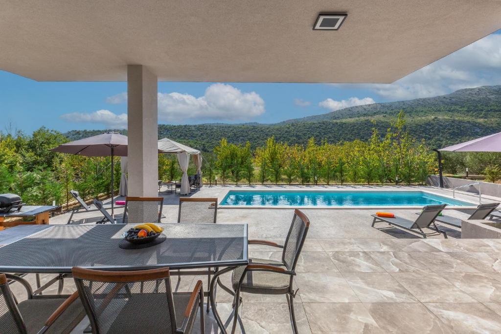 a patio with a table and chairs and a swimming pool at Holiday House Omis - Naklice in Omiš