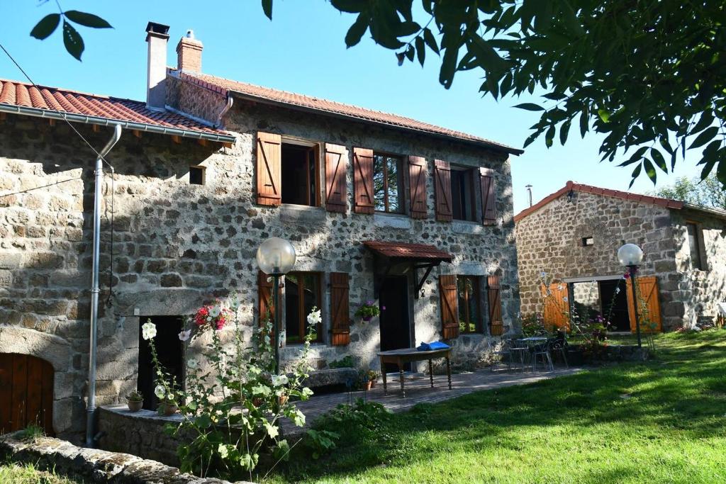 Una antigua casa de piedra con una mesa en el patio. en Chambres d'hôtes - Les Fayards, en Montregard