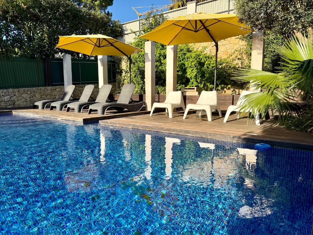 a swimming pool with chairs and umbrellas next to a swimming pool at Serenity Cascais Villa in Cascais