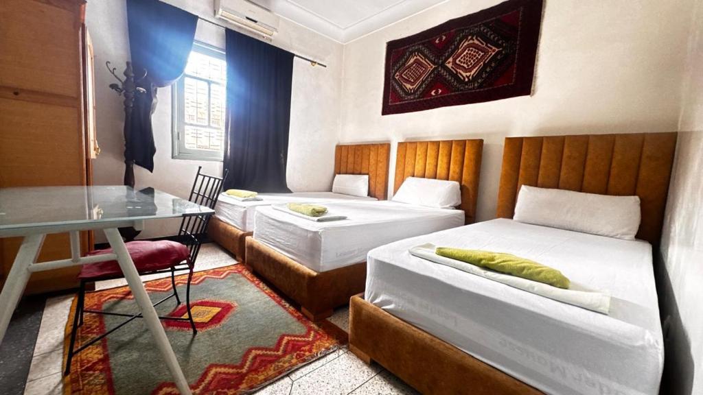 um quarto com duas camas, uma mesa e uma escrivaninha em Les appartements de la Koutoubia em Marraquexe