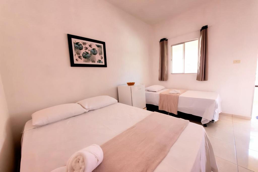 a white room with two beds and a window at Fonte dos Corais - Suíte Onda do Mar in Maragogi