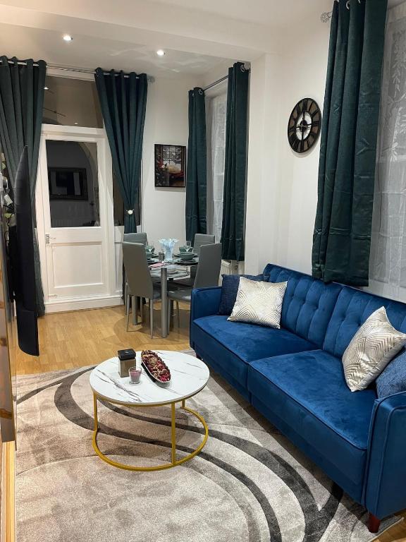 a living room with a blue couch and a table at Acon Heights in London