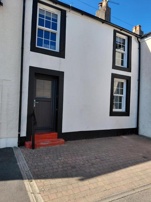 a white and black house with a black door at Maggies Cottage in Little Broughton