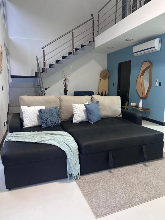 a black couch in a living room with a staircase at Loft en San José de pinilla avellanas guanacaste in San José Pinilla