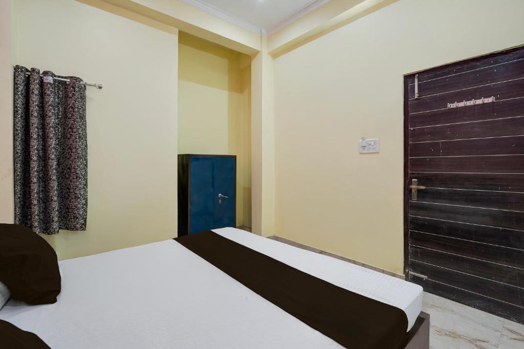 a bedroom with a bed and a black door at Hotel O BLISS INN in Chinhat