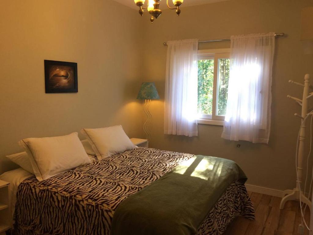 uma cama num quarto com uma janela em Hospedagem domiciliar Gramado em Gramado