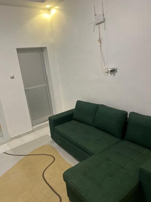 un sofá verde en una sala de estar con ventana en Fatidel, en Thiès