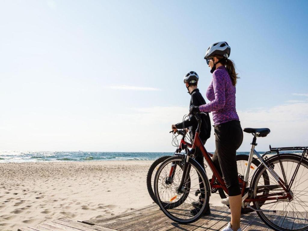 a woman riding a bike on the beach at Comfortable, single-story holiday homes in Łazy
