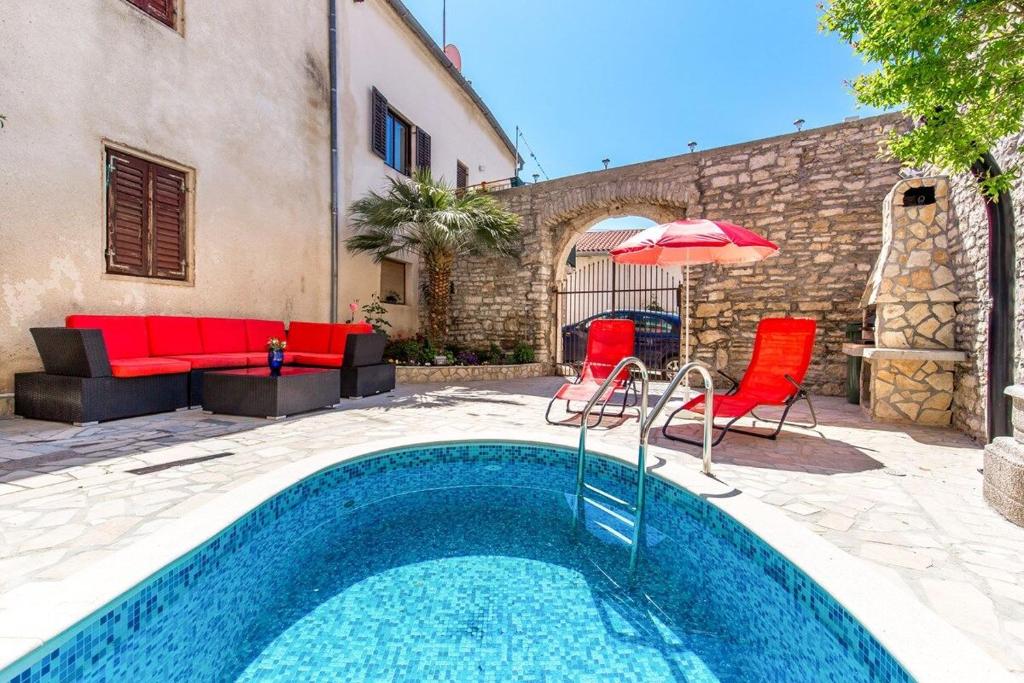 einen Pool mit Stühlen und einem Sonnenschirm sowie eine Terrasse in der Unterkunft Apartments Samia in Medulin