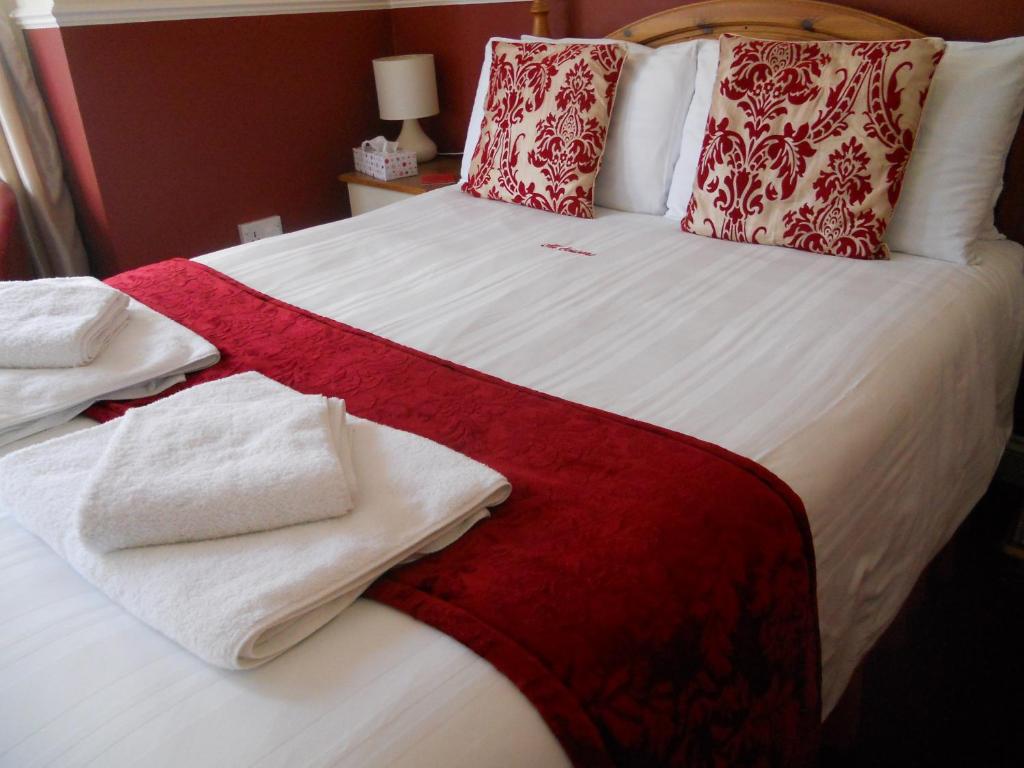Una cama grande con toallas rojas y blancas. en All Seasons Guest House, en Great Yarmouth