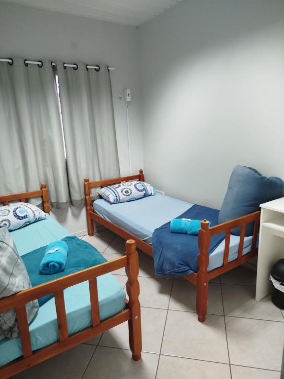 two beds and a chair in a room at Pousada Central Quarto 2 in Joinville