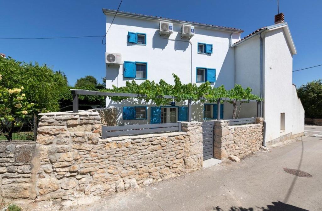 een wit huis met een stenen muur bij House Bernarda in Medulin