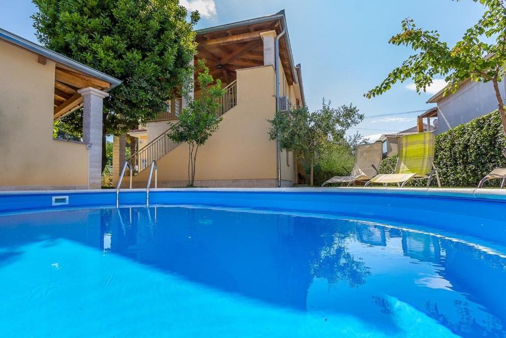a blue swimming pool in front of a house at Villa Cera in Vodnjan