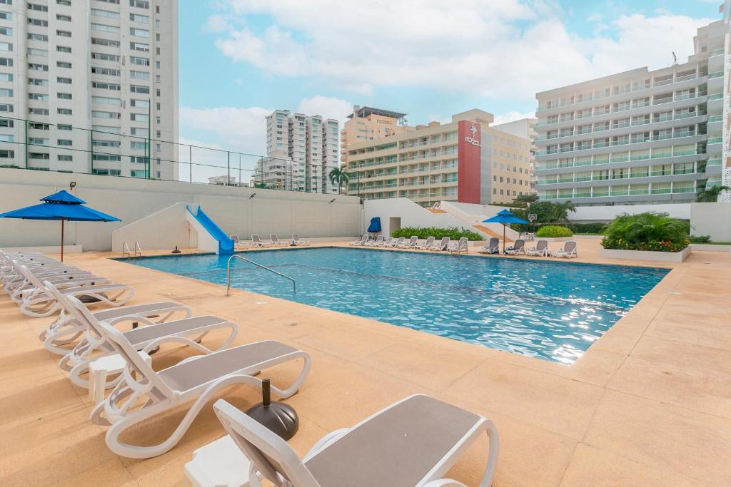 a swimming pool with chairs and umbrellas on a building at Amazing Condo Ocean View By Bamboo Skylife in Acapulco