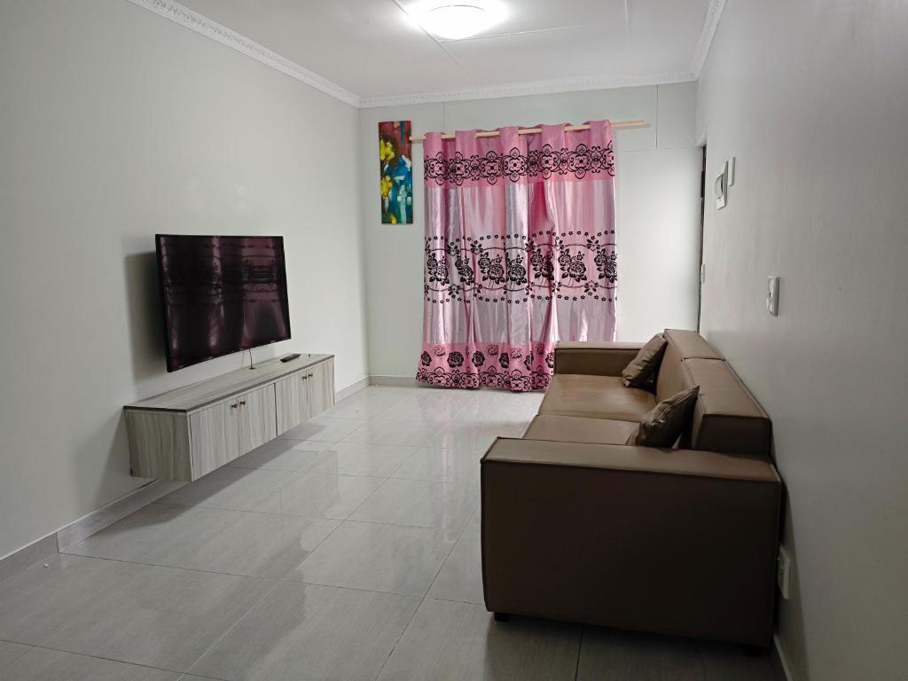 a living room with a couch and a flat screen tv at Spring Cottage in Walvis Bay