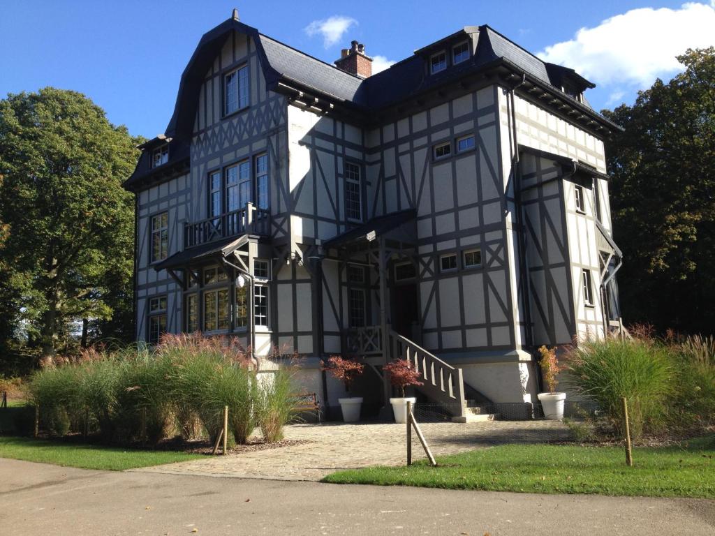 a large black and white house with a porch at Domaine des Bruyères in Sains-en-Amiénois