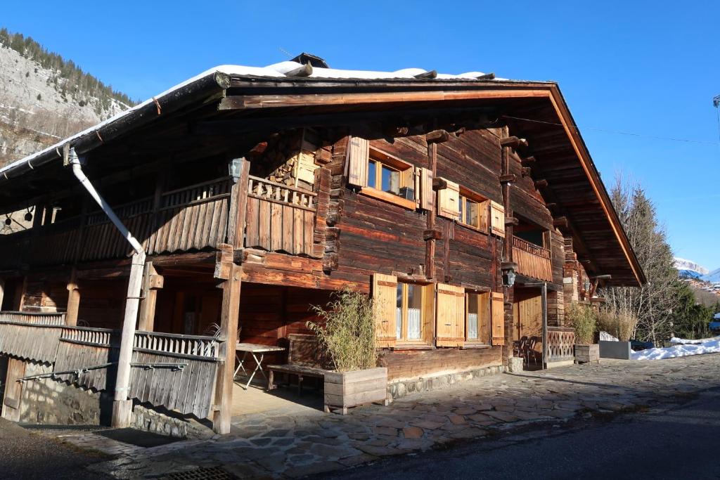 une grande maison en bois avec un toit à la mansarde dans l'établissement CHARMIEUX appartement en chalet typique, au Grand-Bornand