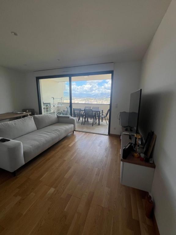 ein Wohnzimmer mit einem weißen Sofa und einem Fernseher in der Unterkunft T2 avec vue panoramique in Ajaccio