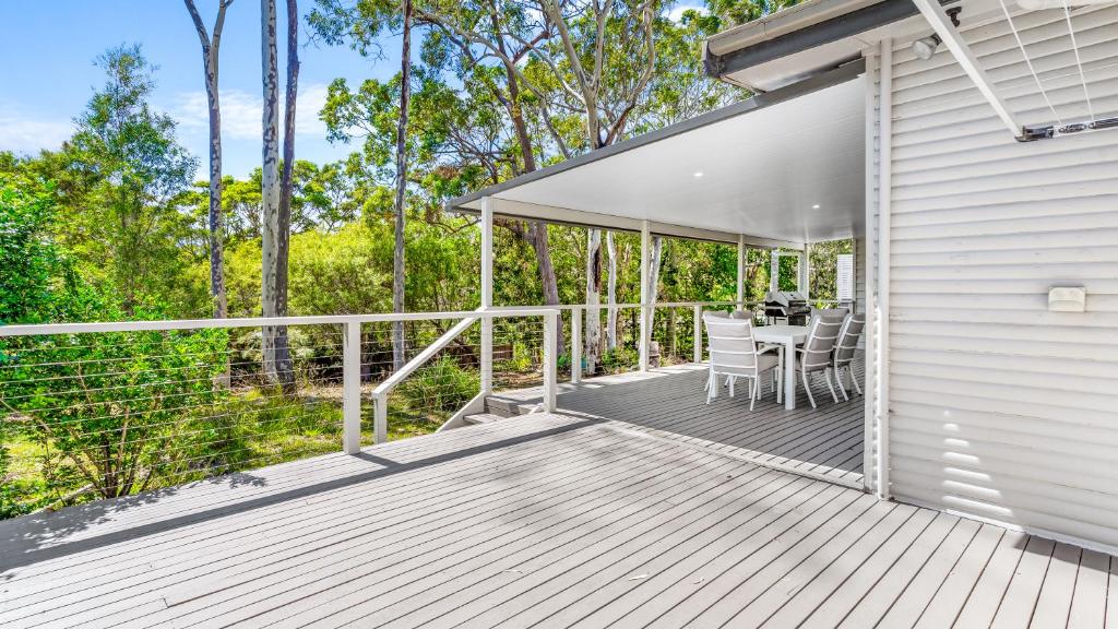 Elizabeth Beach Guest House في Elizabeth Beach: سطح خشبي به طاولة وكراسي