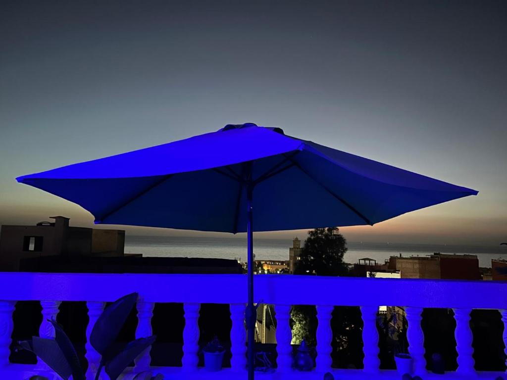 Una sombrilla azul colocada encima de un balcón. en Black Pearl surf yoga and skate house, en Tamraght Ouzdar