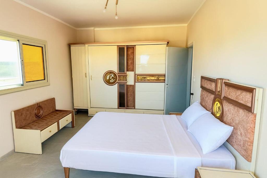 a bedroom with a large white bed and a kitchen at Rock House in Marsa Alam City